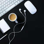 close up shot of a keyboard beside a cup of coffee on a black surface