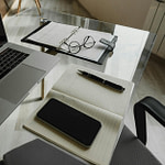 a glass table with a laptop and a notebook