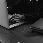 grayscale photo of a person typing on a laptop