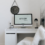 an imac computer over a white wooden desk