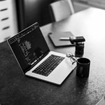 monochrome photo of coffe beside a laptop