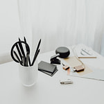 pens in cup and flash drive on white desk