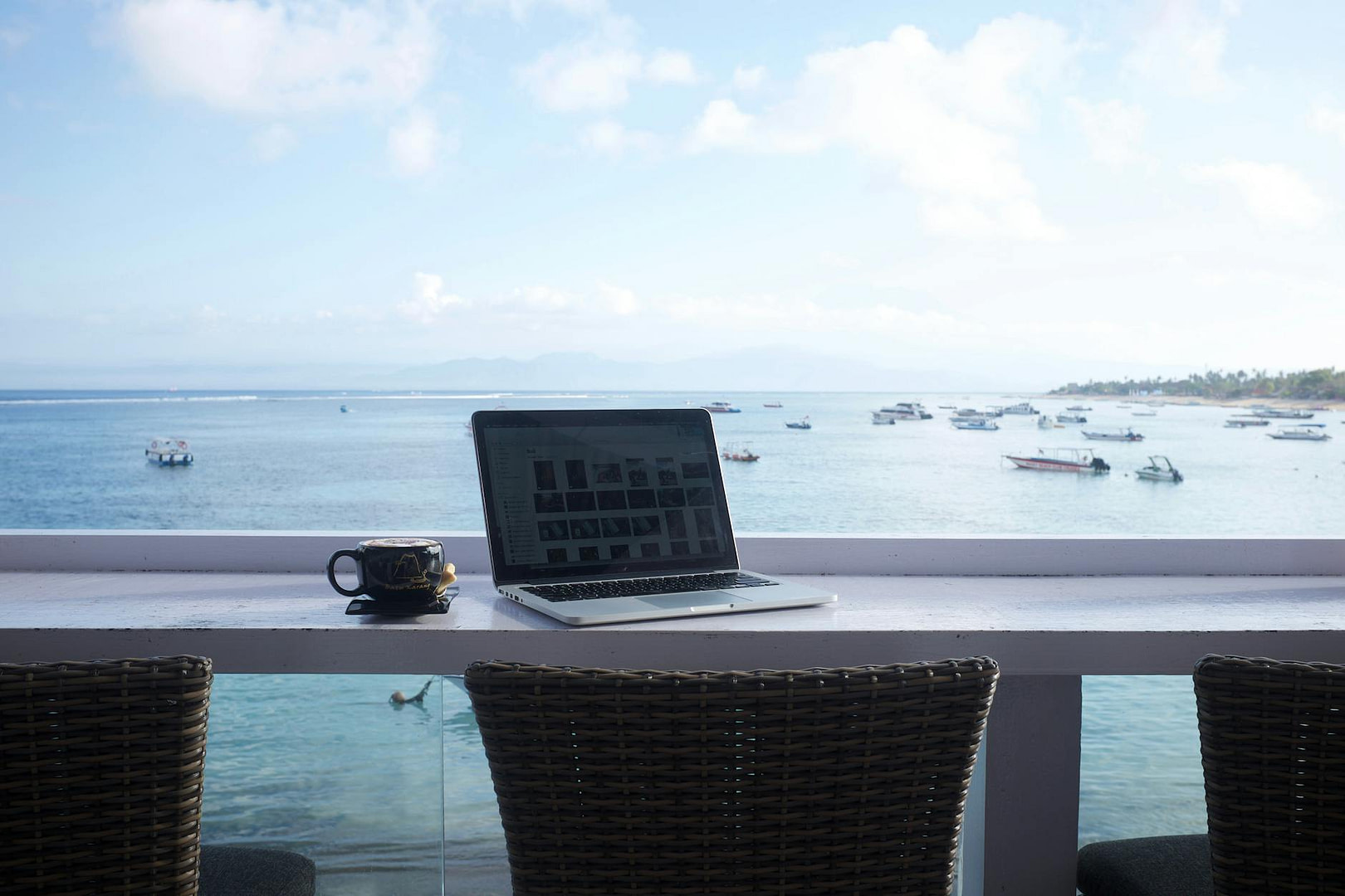 a laptop on a table near glass windows with the sea view