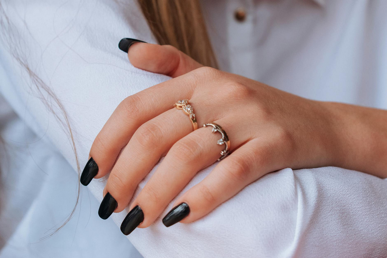 a finger wearing rings with black nails