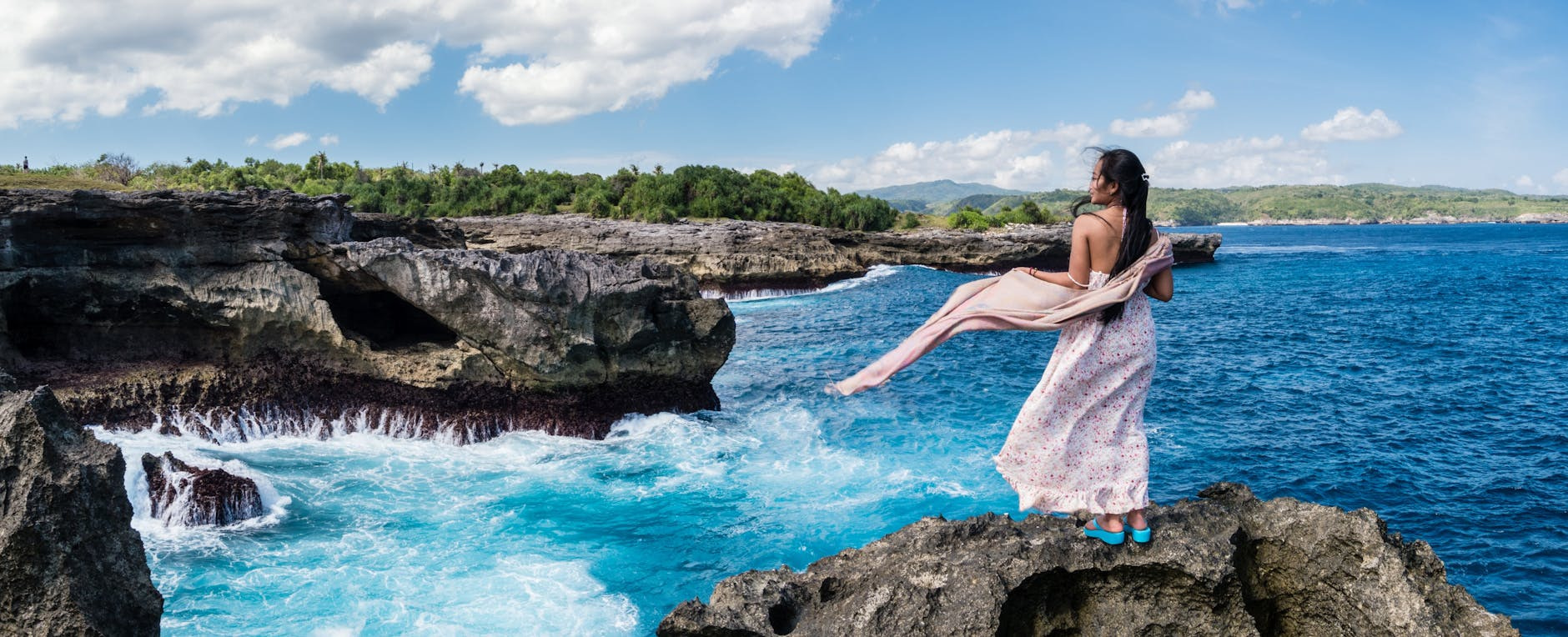 photography of woman standing on rock in front of sea