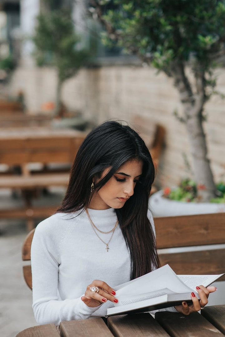serious ethnic woman reading diary in outdoor cafe