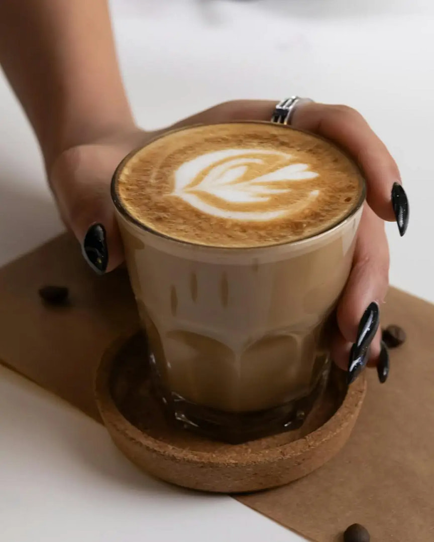hand of a woman picking up a glass of coffee