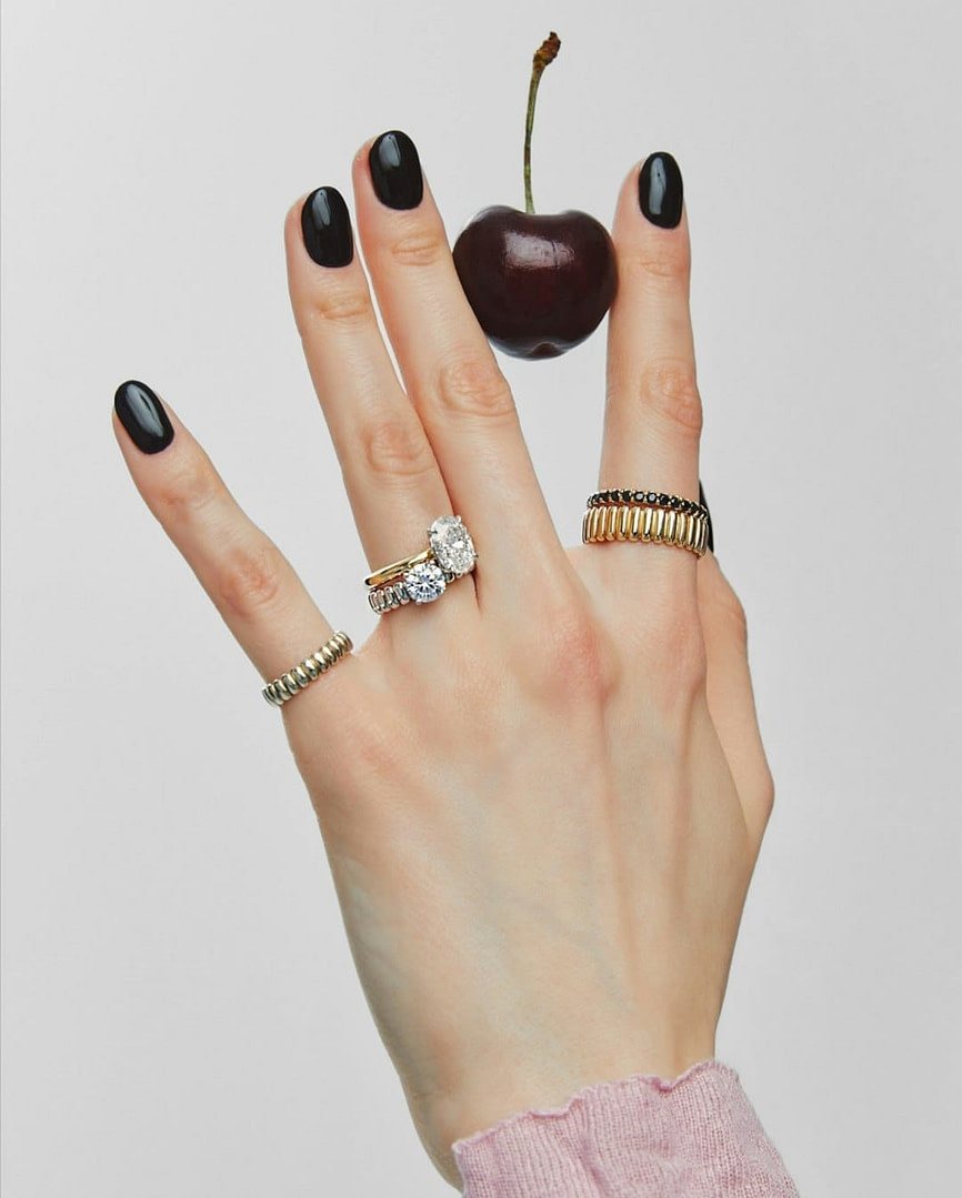 Hand with rings balancing a cherry.